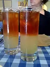 Deux verres remplis de liquide. La moitié inférieure est jaune ; la moitié supérieure est orange. Les deux moitiés ne se mélangent pas.
