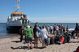 Un bateau déposant ses passagers sur une plage de sable.