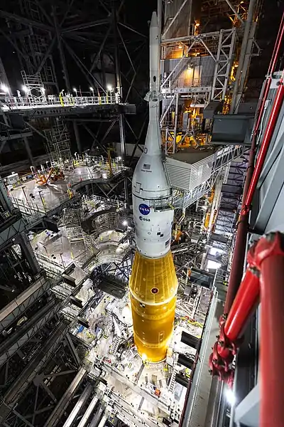 La partie supérieure du lanceur dans le VAB. De haut en bas : la tour de sauvetage, le vaisseau Orion et l'adaptateur de forme tronçonique qui encapsule l'étage supérieur de la fusée (mars 2022).