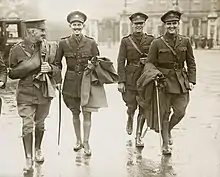 Un groupe de quatre hommes en uniforme marchant le long d'une rue.