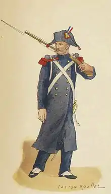 Soldat napoléonien à pied, tenant son fusil sur l'épaule gauche, portant un bicorne avec un petit plumet tricolore, des épaulettes rouges, une longue veste bleu foncé, un pantalon bleu foncé, avec un paquetage et un sabre sur le côté gauche.