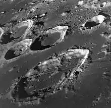 Photographie en couleur de cratères sur la Lune, laissant apparaître un paysage accidenté.