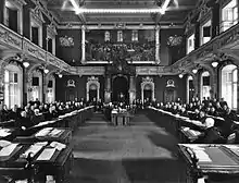 Photographie noir et blanc de l'intérieur d'une assemblée politique avec les députés à leur siège.