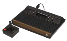 Console de jeux vidéo (boite noire et marron comportant des interrupteurs, avec une manette de jeu).