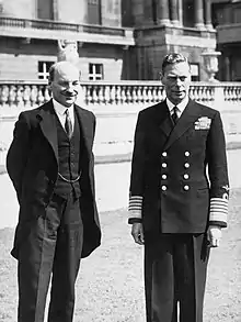 George VI en uniforme d'amiral et Attlee en costume se tiennent devant une balustrade extérieure