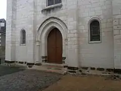 Photographie en couleurs de la façade d'une église avec de grosses pierres brunes au niveau du sol