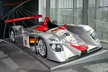 Voiture gris argent, vue de trois-quarts, exposée dans un musée.