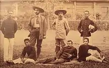Photographie représentant sept hommes (trois Blancs, quatre Asiatiques) dont plusieurs en uniforme. Auguste Pavie, âgé d'une cinquantaine d'années, est vêtu en civil, barbu et coiffé d'un chapeau.