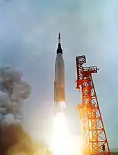 Vue d'une fusée au décollage à côté de la tour de lancement.
