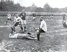 Photographie en noir et blanc de plusieurs joueurs de football sur une pelouse.