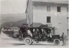 Photo ancienne noire et blanche d'un autocar à l'arrêt devant un hôtel.