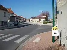 L'avenue de la mairie. La borne kilométrique au premier plan montre l'appartenance à la voirie départementale de cette rue.