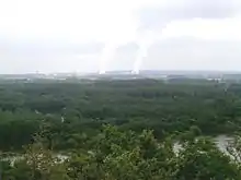 Photographie en couleurs représentant les panaches de vapeur d'une centrale nucléaire au loin.