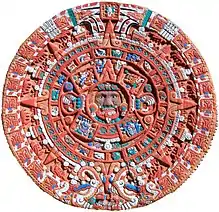 Pièce de terre cuite rouge figurant au centre un masque à la langue pendante et aux yeux exorbités, entouré de cercles concentriques pleins de symboles aztèques