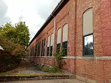 Mur d'un bâtiment en brique avec beaucoup de fenêtres.