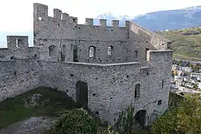 Bâtiment sans toit et dont les portes sont protégées par des barreaux. Le sommet des murs sont crénelés.