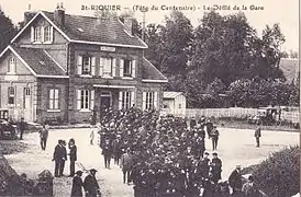 Carte postale ancienne montrant le bâtiment voyageurs de la gare, avec une foule importante devant son entrée.