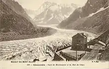 Carte postale en tons sépia représentant une gare dominant un glacier.