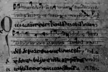 Photographie de mauvaise qualité en noir et blanc d’un manuscrit avec une portée musicale.