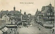 carte postale d'avant la Première Guerre mondiale montrant un kiosque, rue de la République, où se rejoignent deux lignes de tramway