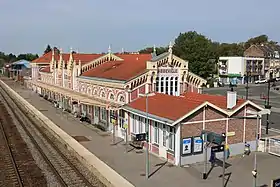 Photographie du bâtiment voyageurs (vu du côté voies, sur la gauche par rapport au corps central) de la gare d'Abbeville, par temps ensoleillé.