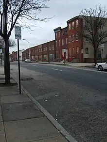 Photo d'une rue de Baltimore ressemblant à celles montrées dans la série avec des constructions en briques rouge.