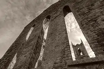 Photographie en noir et blanc d'un clocher vu en contre-plongée à travers des fenêtres en lancettes.