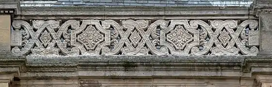 Au sommet de l'entablement de la deuxième élévation de la façade néo-classique sud, trône une balustrade richement décorée, où des quadrangulaires (losange) et octogonaux décorés d'une rose chacun (la rose est un des emblèmes de la Vierge Marie) sont entrelacés entre dans un système complexe de volutes bourgeonnant en certains endroits avec des feuilles d’acanthe. C'est un superbe entrelacs dont les limites sont les hauts des pilastres qui servent de minces et légers contreforts. Les parties extrêmes des volutes encadrent deux médaillons rectangulaires sans ornements qui sont des supports quelques les volutes sont liées pour éviter de casser et de tomber. L'élément est en pierre de Vernon.