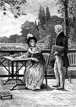 Un homme s'adresse à une jeune femme en train d'écrire à sa table sur une terrasse qui domine un parc.