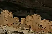 habitations rectangulaires en banco (terre crue) devant une falaise abrupte