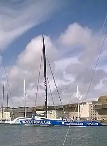 Vu de trois quarts avant, un trimaran géant amarré au ponton.