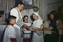 Cérémonie de baptême le 27 juillet 1944 de plusieurs bébés nés à la maternité de la maison maternelle départementale du Calvados, au château de Bénouville.