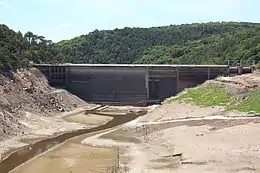 photo du barrage en béton barrant la vallée asséchée