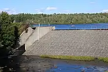 Vue d'un barrage et de son déversoir avec des plaisanciers à pédalo