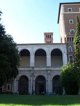 Image photographique d'une façade d'édifice composée trois arches sur piliers sur deux ordres.