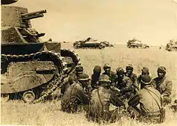 Photo en noir et blanc d'hommes assis auprès de chars de combat.