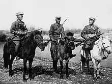 Photo en noir et blanc de trois hommes en tenue militaire à cheval.