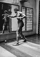 Photographie de presse d'un boxeur s'entraînant devant un miroir dans une salle de sport.