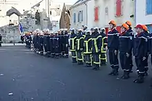 Photographie d'un peloton de pompiers lors d'une cérémonie.