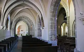 Vue en perspective de l’intérieur d’une église, avec une succession d’arches en ogive brisée.