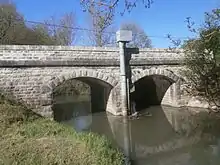Photographie en couleurs d'un pont à deux arches enjambant un cours d'eau.