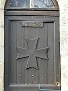 Croix de Malte sculptée sur la porte de la chapelle Saint-Roch.