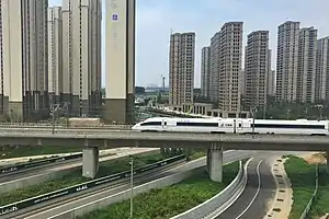 Urbanisation dense, architecture de grande hauteur. Voies rapides. LGV Pékin - Canton, 2 298 km à 300 km/h (ici près de Zhengzhou)Ligne ouverte en janvier 2013