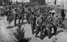 Rapatriement de prisonniers de guerre belges à Chiny avant 1945 (on aperçoit un militaire d'escorte avec un casque allemand à l'arrière plan).