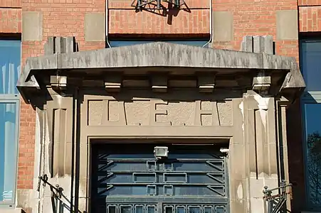 Le tympan du portail frappé des lettres « U.E.H »(« Usines Émile Henricot »).