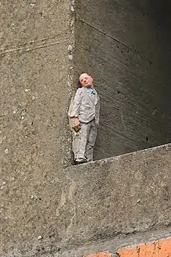 Statuette d'Isaac Cordal nichée dans une cheminée(voie des Hennuyers).