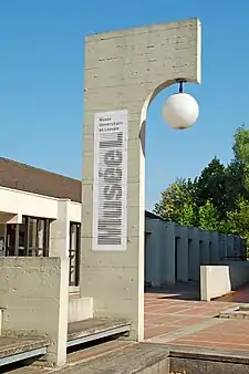 Logo du Musée L sur une des colonnes en équerre de la place des Sciences.