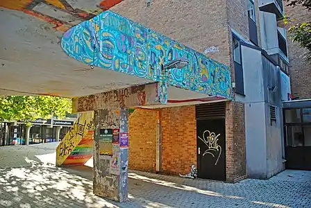 Passerelle en « béton brut » ornée de peintures murales du « Kosmopolite Art Tour 12 ».