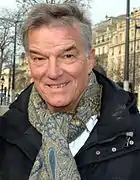 Photographie d'un homme souriant aux cheveux grisonnants.