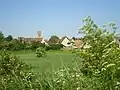 Le vieux Bénouville, avec l'église Notre-Dame, vu du chemin de halage du canal de Caen à la mer.